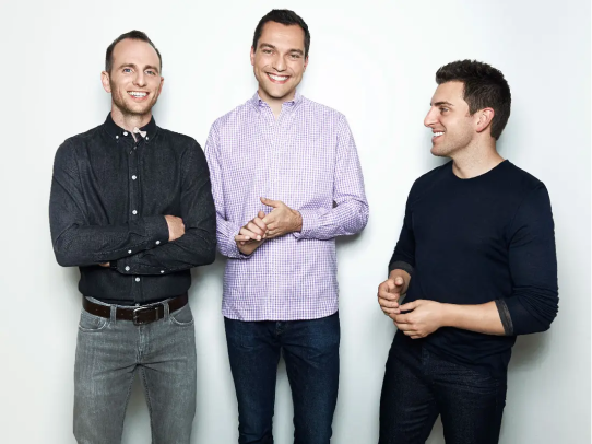 three men smiling in front of a white background